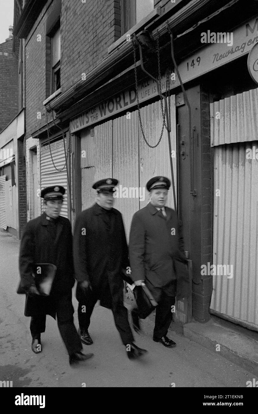 Tre membri dell'Esercito della salvezza camminano lungo una strada durante l'evacuazione dei baraccopoli e la demolizione di Victorian St Ann's, Nottingham. 1969-1972 Foto Stock