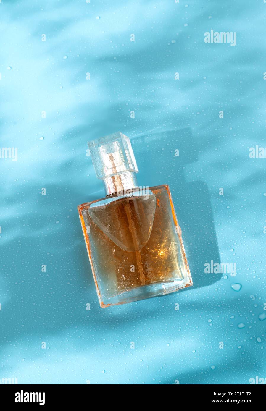 Una bottiglia di profumo su sfondo blu con ombre dure. Posizione piatta e luce dura Foto Stock