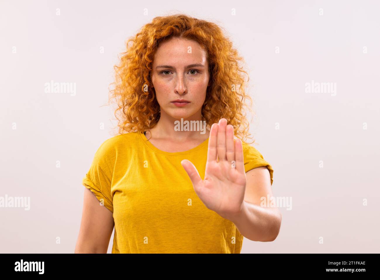 Immagine di una donna seria che mostra il segnale di stop su sfondo grigio. Foto Stock