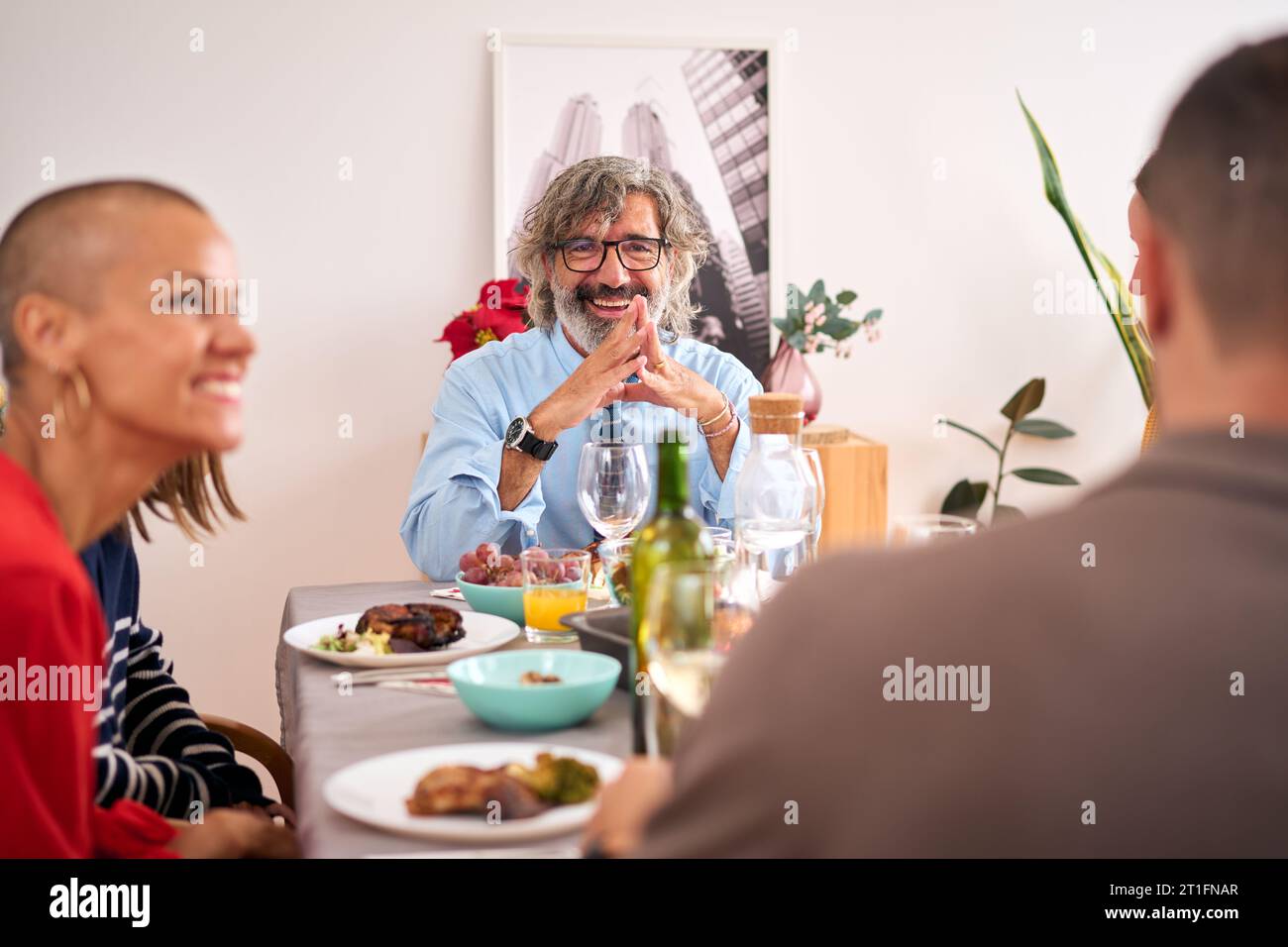 Sorridente famiglia multi-generazionale che si gode il pranzo di Natale insieme a casa. Foto Stock