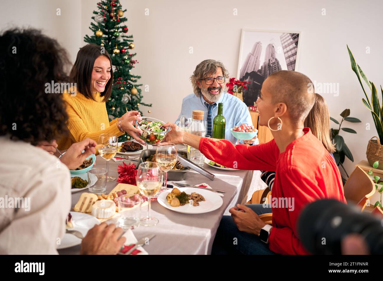 Famiglia felice riunita intorno al tavolo da pranzo durante il pranzo di Natale a casa. Persone che vivono in casa. Foto Stock