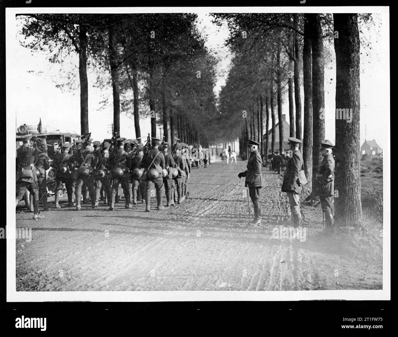 Fotografie di visite reali al fronte occidentale. Le visite reali sono state viste come un modo importante per aumentare il morale. Le truppe irlandesi marciano lungo una polverosa strada alberata. Alcune truppe stanno suonando le cornamuse. Gli spettatori guardano dal lato della strada. In lontananza ci sono un certo numero di veicoli e un uomo su un cavallo grigio. Il duca di Connaught era il terzo figlio della regina Vittoria. Il generale Plumer fu celebrato per aver guidato la vittoriosa battaglia di Messines Ridge nel 1917. [L'originale recita: 'FOTO UFFICIALE SCATTATA SUL FRONTE occidentale - le truppe irlandesi marciano davanti al Duca di Connaught e al generale Sir Herbert Foto Stock