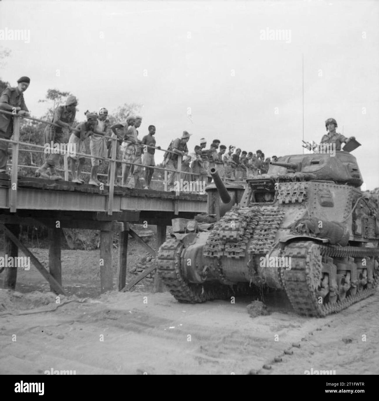 L'esercito britannico in Birmania 1945 un serbatoio di sovvenzione si sposta in modo da supportare il ventiseiesimo Indian divisione di fanteria sull isola Ramree. Da un ponte i soldati e i locali a guardare, Gennaio 1945. Foto Stock