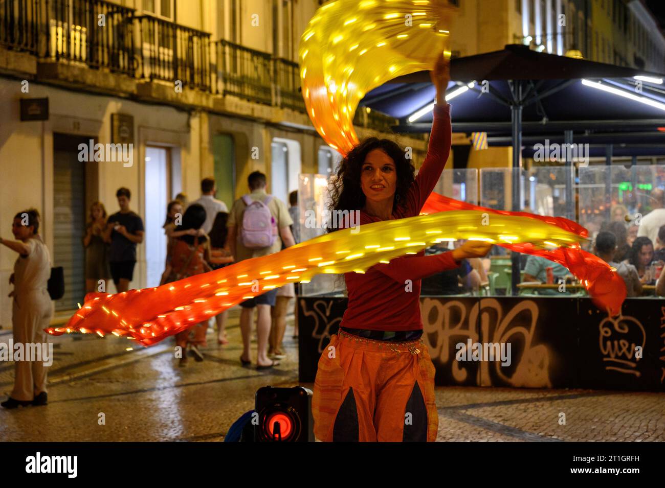 Una ballerina di strada che esegue una danza con sciarpe a Lisbona, Portogallo. Foto Stock