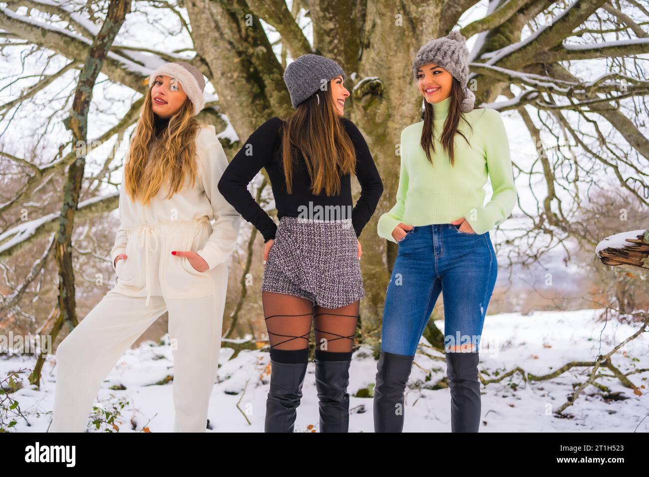 Tre graziosi amici caucasici che si godono la neve in inverno sotto un albero, vacanze invernali sulla neve Foto Stock