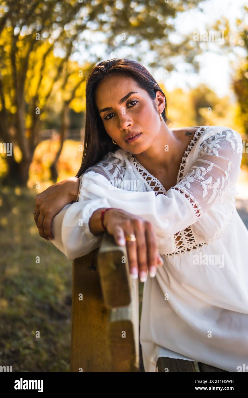 Stile di vita estivo, una giovane bruna latina che si gode un parco con un vestito bianco Foto Stock