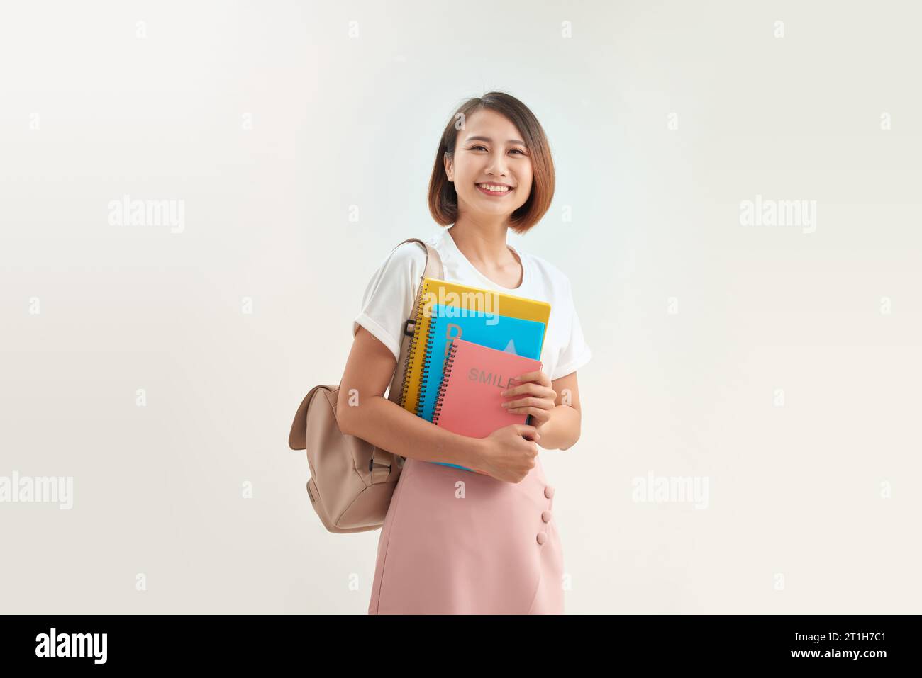 Ritratto di una giovane studentessa asiatica che tiene libri di esercizi. Foto Stock