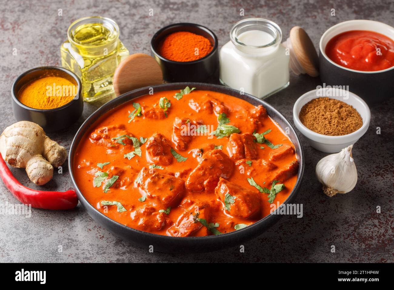 Tradizionale piatto indiano britannico di pollo tikka masala con carne di curry piccante in salsa cremosa su sfondo di cemento scuro per primo piano. Orizzontale Foto Stock