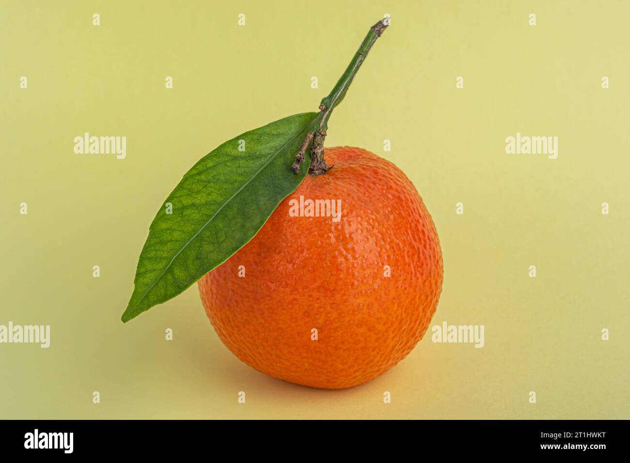 Tangerini o clementine con foglia verde su sfondo giallo primo piano Foto Stock