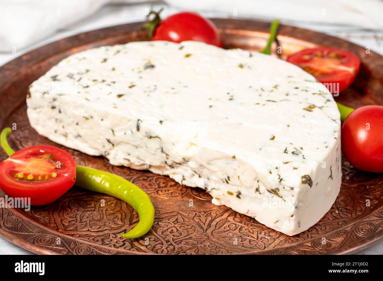 Formaggio alle erbe su un piatto di rame. Fette di formaggio alle erbe su fondo di legno. nome locale otlu peynir. Primo piano Foto Stock