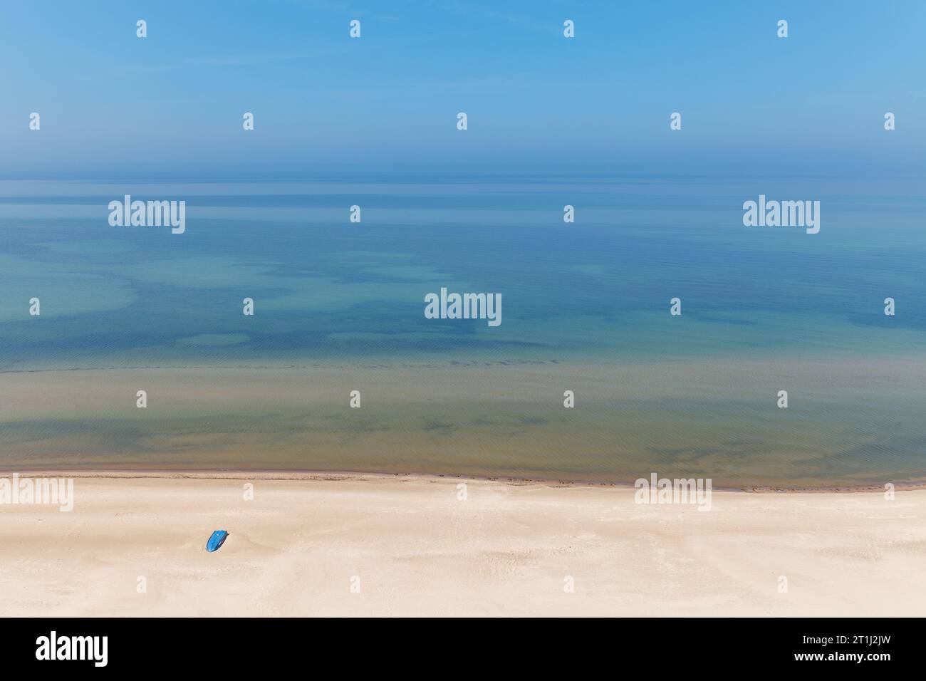 Paesaggio aereo della spiaggia estiva con un peschereccio blu solitario che riposa sulla sabbia. Mar Baltico, Lituania Foto Stock