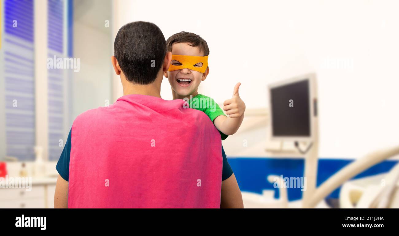 Il mio adorabile super papà. Il bambino fa un cartello con le mani che ridono felicemente nell'ufficio dentista Foto Stock