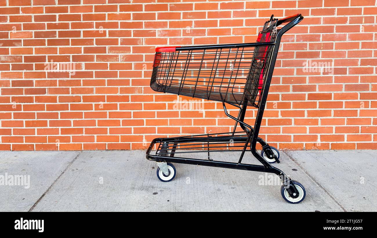Carrello della spesa vuoto all'esterno con sfondo mattone Foto Stock