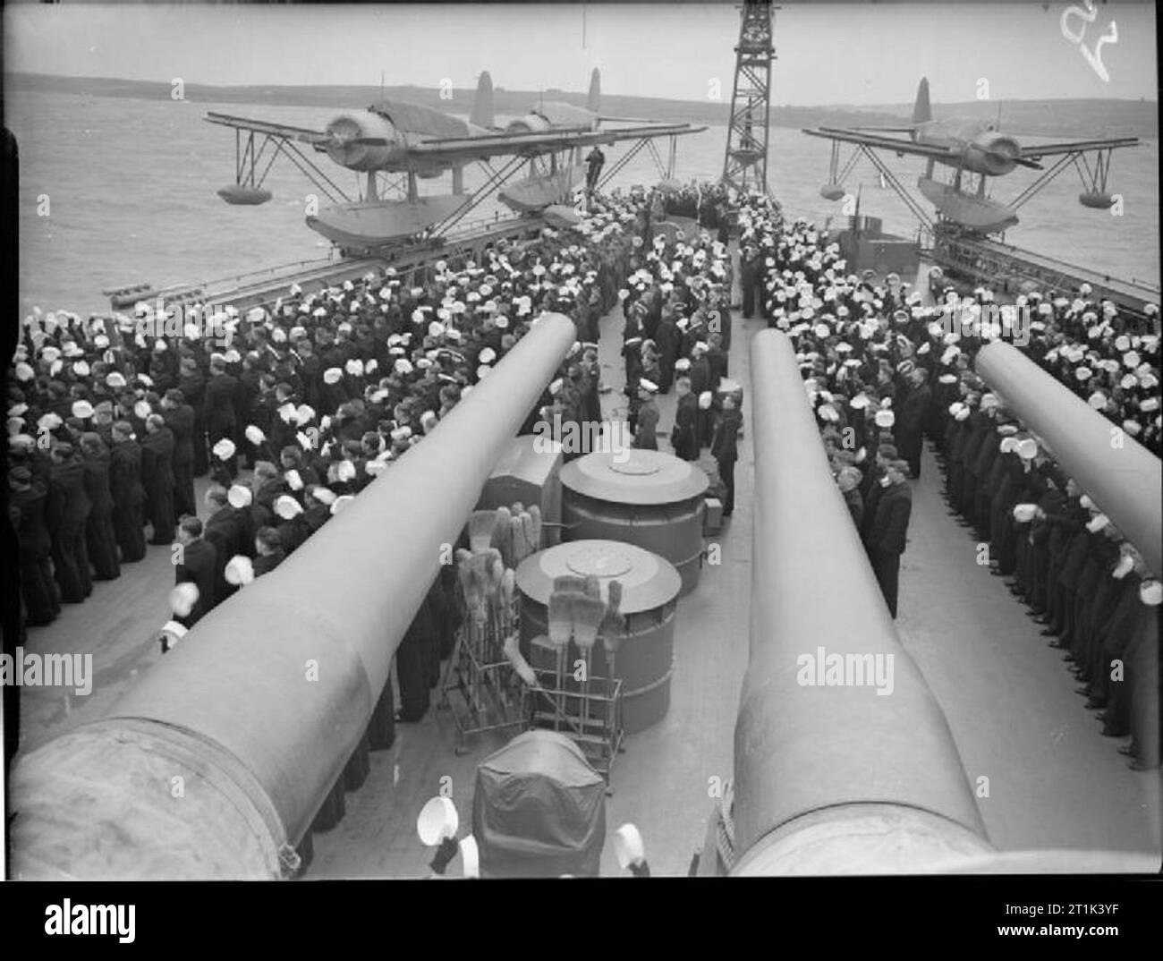 La Royal Navy durante la Seconda guerra mondiale la nave della società dell'US Corazzata USS WASHINGTON dare tre acclamazioni come HM King George VI passa la loro nave presso la Scapa Flow. Nota le tre Vought-Sikorsky Kingfisher aeromobile sul loro catapulte a poppa della nave, botti di tre della corazzata di 16 pollici pistole possono essere visti in primo piano. Foto Stock