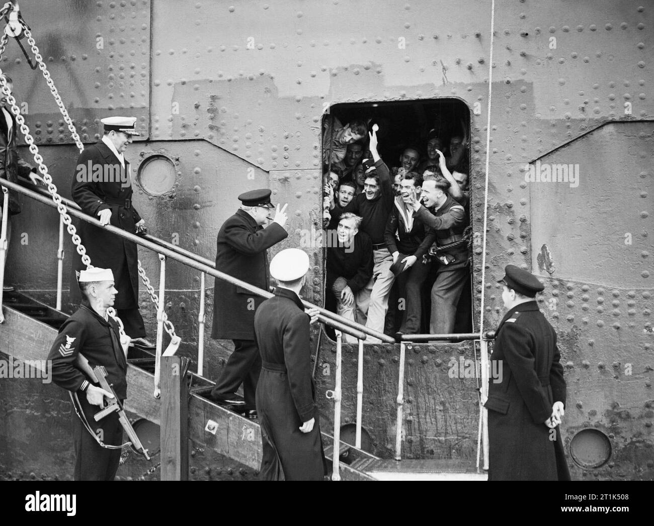 Winston Churchill durante la Seconda Guerra Mondiale il Primo Ministro dà il segno della vittoria in risposta ai buoni auspici dei marinai, aviatori etc a bordo come egli approda da SS QUEEN MARY all'arrivo negli Stati Uniti. Nella parte posteriore è Admiral Adolphus Andrews del Navy US. Foto Stock