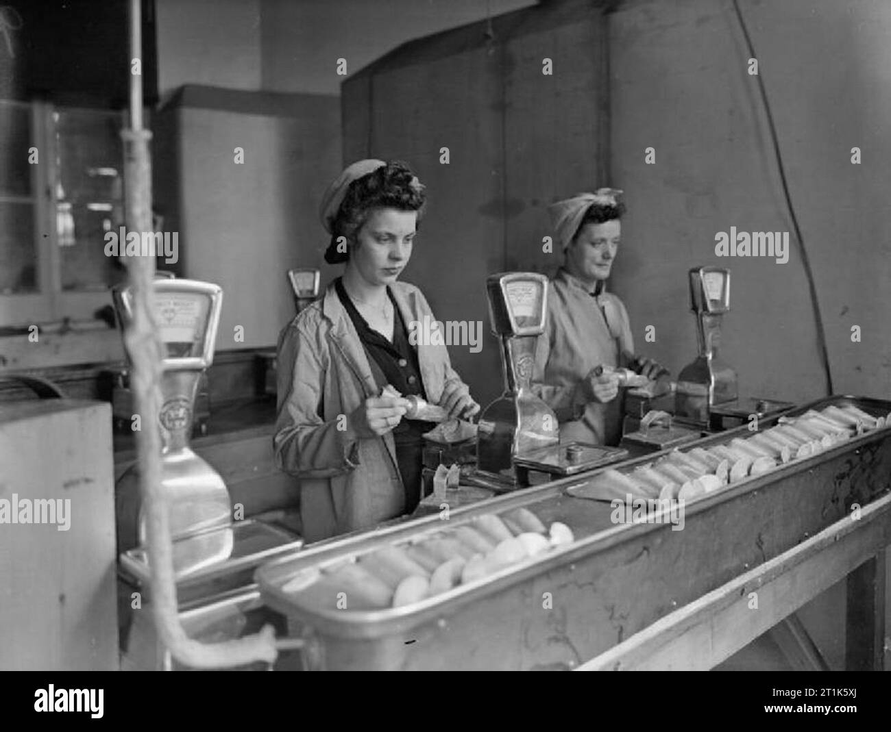 La vita al Royal Navy armamento Depot Priddy's Hard, Gosport, 25-30 luglio 1944 a RNAD Priddy's Hard, Gosport, Gladys Mingay, di età compresa tra i 19 e Gladys Cox, 39 anni, pesatura esplosivo RDX per il riempimento di naval due gusci di cancelletto. Foto Stock