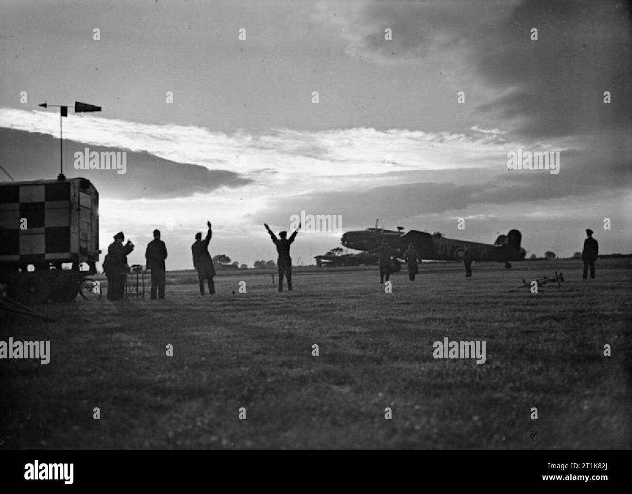 Royal Air Force Bomber Command, 1942-1945. Il comandante della stazione a Pocklington, nello Yorkshire, segnali Handley Page Halifax B Mark II Serie I (speciali), DT742 'Y-O', di n. 102 Squadrone RAF, pilotato dal sergente T H Dargavel, per iniziare la sua corsa di decollo in una notte il raid per la Schneider fabbrica di armamenti a Le Creusot, Francia. Foto Stock