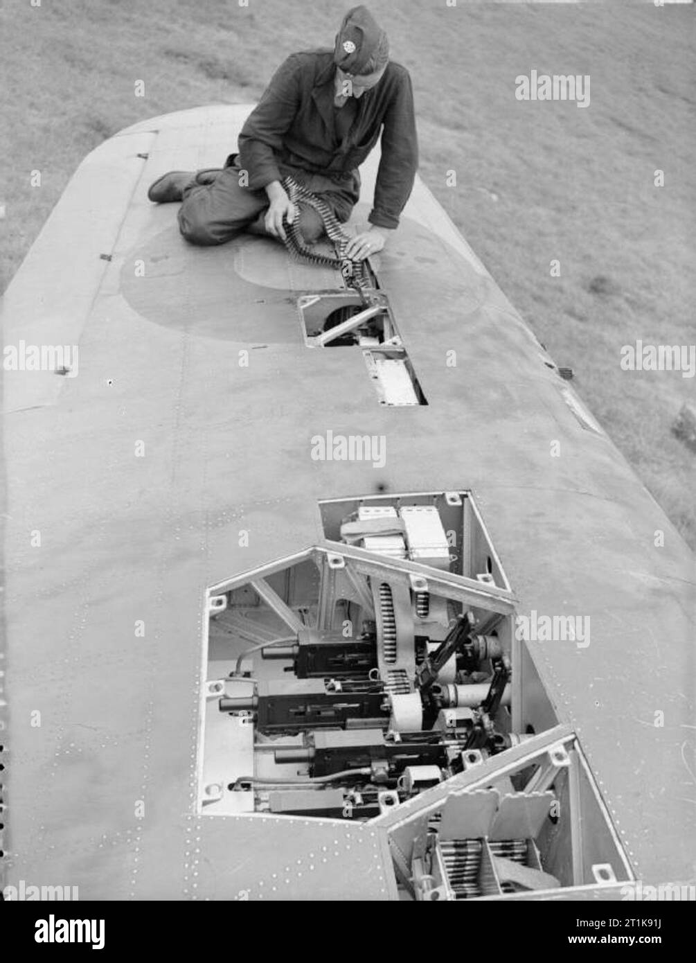 Royal Air Force Fighter Command, 1939-1945. Un Hurricane Mk IIB di n. 3 Squadron RAF è nuovamente armato a Hunsdon, Hertfordshire. Un armourer sta alimentando 303 munizioni nel magazzino della più lontana della porta una coppia esterna di Browning pistole di macchina: la scoperta dei pantaloni e delle riviste di quattro pistole più interne sono in primo piano. Foto Stock