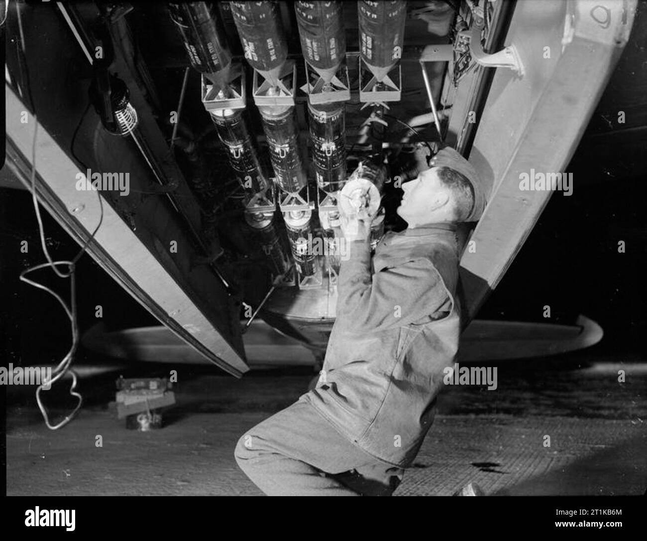 Royal Air Force - la seconda forza aerea tattica, 1943-1945. Un armourer, portando Aircraftman H Cavaliere di Cliffe-a-Hoo, Kent, carichi 19-lb 4.5 pollici flash fotografico bombe in un De Havilland PR Mark XVI di n. 140 Squadrone RAF a B58/Melsbroek, Belgio, prima di una notte fotografico-reconnaissance sortie. Foto Stock
