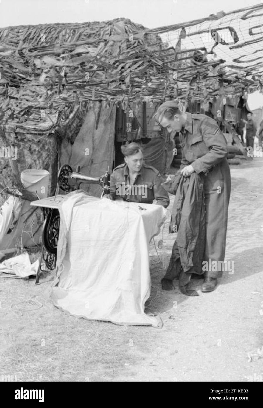 Royal Air Force - la seconda forza aerea tattica, 1943-1945. Un macchinista di cucitura di n. Gruppo di 84 unità di supporto, viene chiesto se egli è in grado di riparare un caporale della tuta strappata a Merston, Sussex. Foto Stock