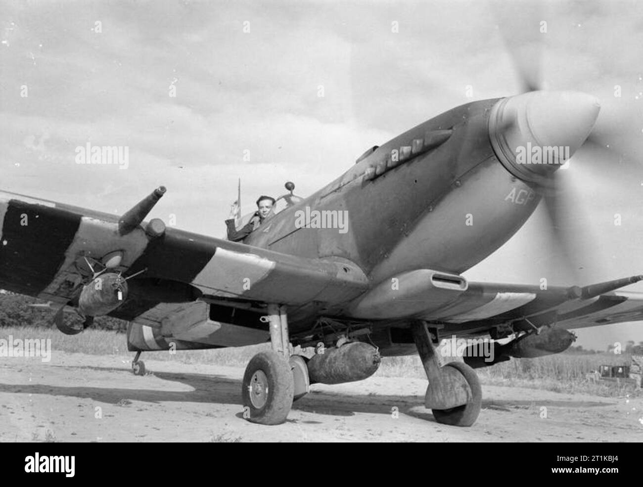 Royal Air Force - la seconda forza aerea tattica, 1943-1945. Wing Commander una pagina di G, leader di n. 125 Ala, nell'abitacolo della sua Supermarine Spitfire Mk IXE 'AGP', con un 500-lb GP bomba sotto la fusoliera e due da 250 lb GP bombe sul parafango rack, pronto a decollare in B11/Longues, in Normandia. Più tardi lo stesso giorno, la pagina è stata a sparare giù il suo quattordicesimo aereo nemico, un Messerschmitt Bf 109, tornando a Longues ferito alla gamba e il suo aereo danneggiato da anti-incendio di aeromobili. Foto Stock