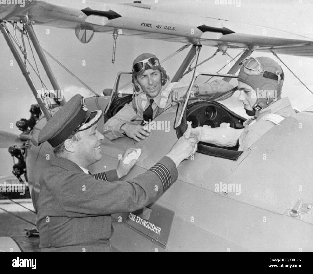 Royal Air Force- British la formazione di volo negli Stati Uniti, 1941-1945. Gruppo capitano D V Carnegie, capo della RAF delegazione a Washington DC, si congratula con il volo Stonier Leader per essere il primo RAF cadet per volare dall'enigma Istituto aeronautico di formazione airfield, al campo Carlstrom, Arcadia, Florida. La RAI è Capo istruttore di volo, Jack Hunt, guarda dalla parte anteriore abitacolo della Boeing Stearman PT-17. Foto Stock