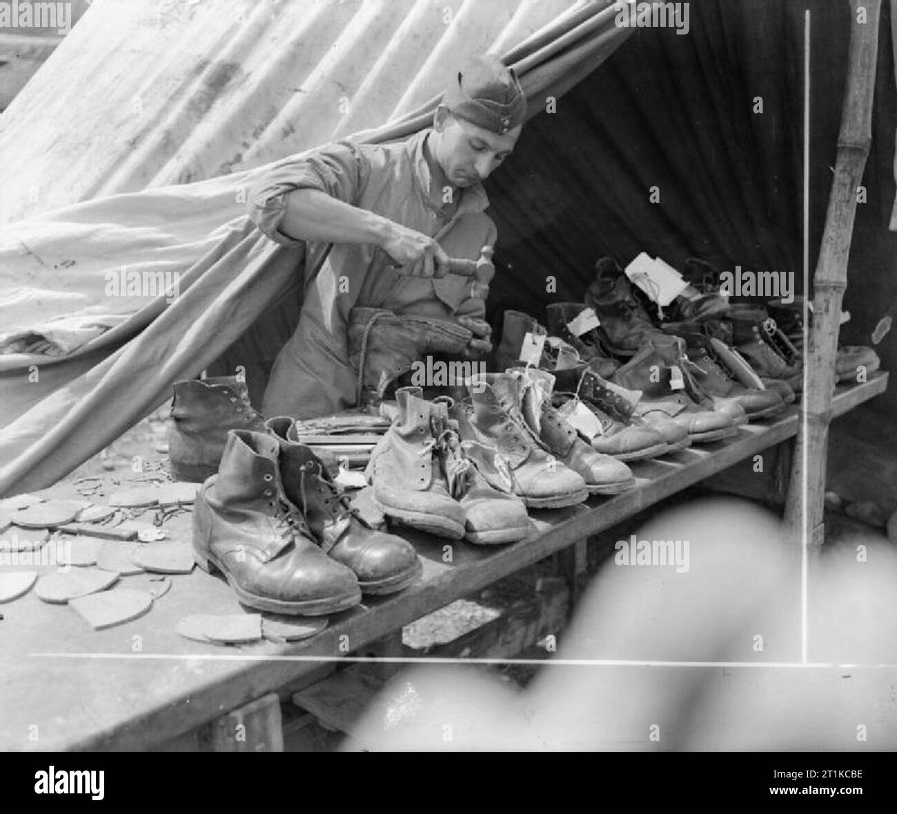 Royal Air Force - L'Italia, i paesi dei Balcani e del sud-est Europa, 1944-1945. Leader Ponte Aircraftman di Bolton, Lancashire, il ciabattino di un campo dello squadrone RAF reggimento, rammendo scarponi al loro accampamento appena dietro la linea del fronte nei pressi di Cassino, Italia. Due squadroni di campo sono state utilizzate nel ruolo di fanteria sul fronte di Cassino, essendo posto sotto il comando della seconda Nuova Zelanda Divisione e 4 Divisione britannica rispettivamente dal 24 aprile al 27 maggio 1944. Foto Stock