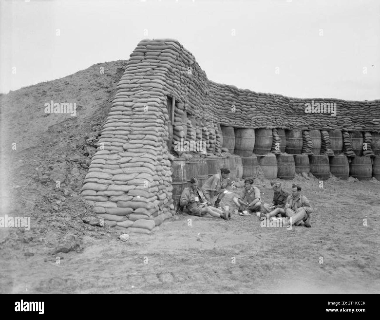 Royal Air Force - L'Italia, i paesi dei Balcani e del sud-est Europa, 1944-1945. Personale di terra di n. 43 Squadron RAF a mangiare la loro razione di cibo in un anti-blast di fronte a penna con sacchi di sabbia e botti da vino a Nettuno, Italia. Da sinistra a destra essi sono: Leading Aircraftman H Wiggins di Oxford; sergente di volo F Nunn di Enfield, Middlesex; Sergente K Fackrell di Bexleyheath Kent; Sergente G Crolley di Ayr Scozia, e un sergente L Rogers di Falmouth, Cornwall. Foto Stock