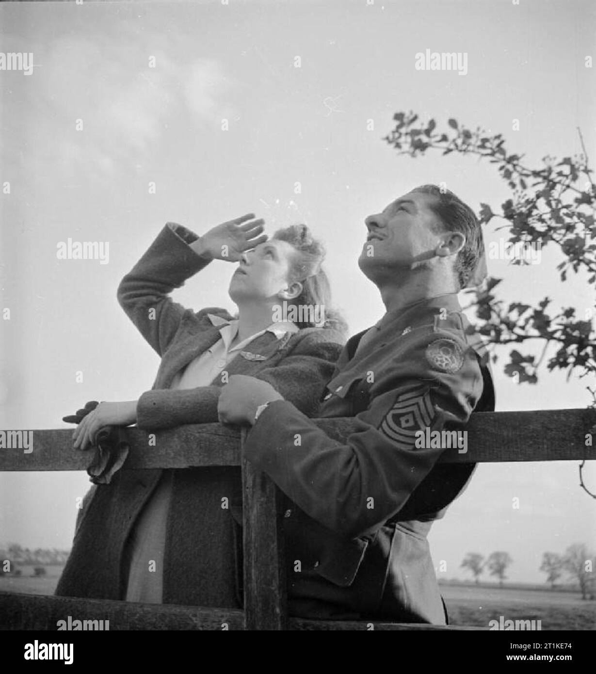 Gli americani in Gran Bretagna, 1942 - 1945 GI Brides: un sergente americano e il suo inglese ragazza guarda i bombardieri di ritorno, Chelveston, Northamptonshire. Foto Stock