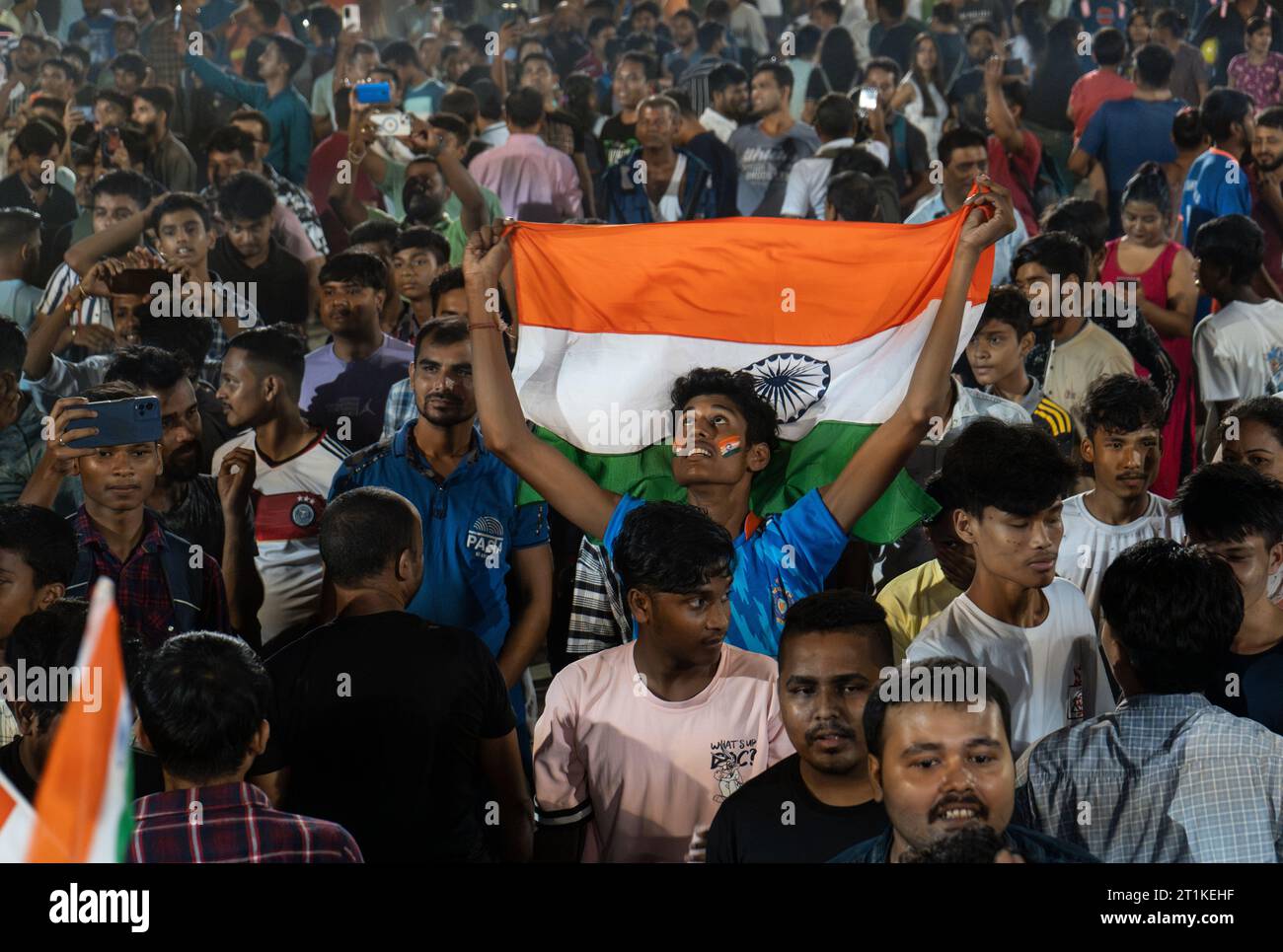 I tifosi indiani di cricket applaudono mentre guardano la partita internazionale di un giorno della Coppa del mondo di cricket maschile 2023 (ODI) tra India e Pakistan sullo schermo di un proiettore in un campo, il 14 ottobre 2023 a Guwahati, Assam, India. L'India ha sconfitto il Pakistan con 7 wicket. Credito: David Talukdar/Alamy Live News Foto Stock