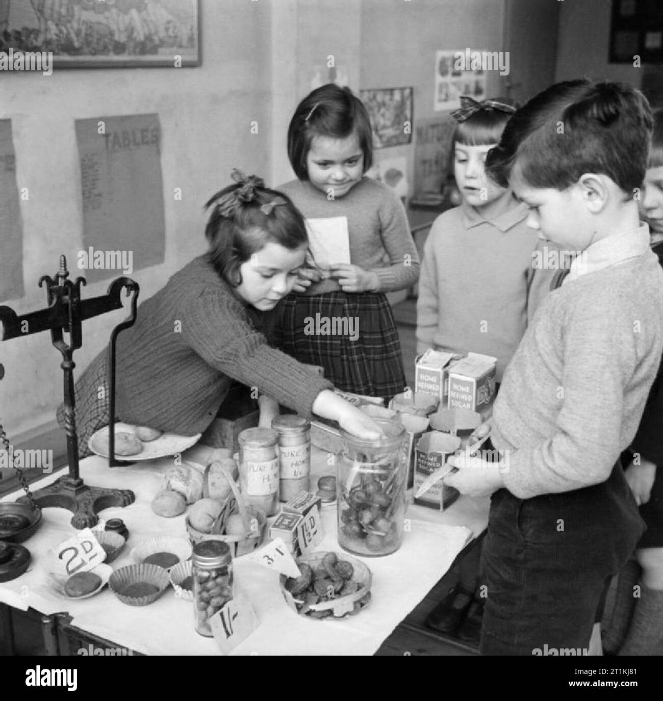 I bambini imparano la matematica sommando i costi di una lista della spesa in un negozio di alimentari in classe alla Fen Ditton Junior School, Cambridgeshire nel dicembre 1944. Foto Stock