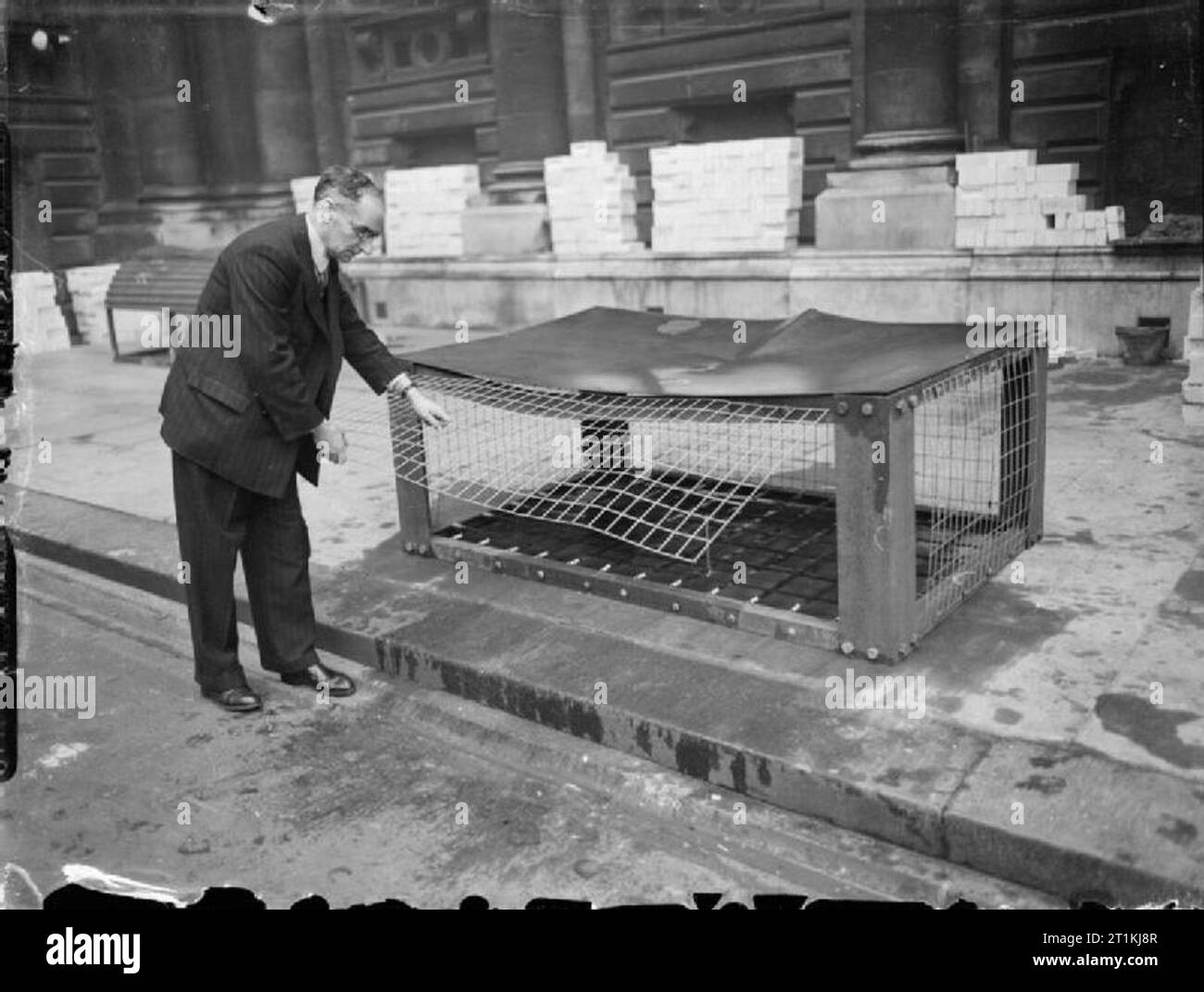 Difesa civile in Gran Bretagna- Morrison Shelter Test, 1941 Un rappresentante del ministero della Sicurezza domestica solleva uno dei lati delle maglie di un Morrison rifugio a seguito di un test per determinare la sua forza e la idoneità come una piscina Air Raid Shelter, Londra, 1941. Foto Stock