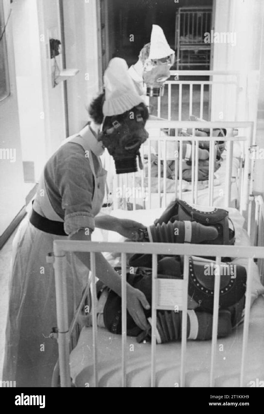 Trapano a gas in un ospedale di Londra- di maschere antigas per bambini sono testati, Inghilterra, 1940 Due infermiere ogni pompa soffietto di un bambino respiratore di gas al fine di fornire al bambino che indossa la maschera con aria, durante un trapano di gas in un ospedale di Londra, 1940. Foto Stock