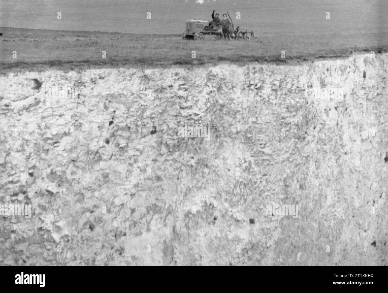 Linea anteriore Farm- agricoltura sulle Bianche Scogliere di Dover, Kent, Inghilterra, Regno Unito, c 1944 agricoltore Gilbert Mitchell e il suo conducente del trattore Signor C Rogers guardare fino a un aeromobile (non mostrato) come andare circa il loro lavoro quotidiano su i campi sul bordo delle Scogliere Bianche di Dover. Foto Stock