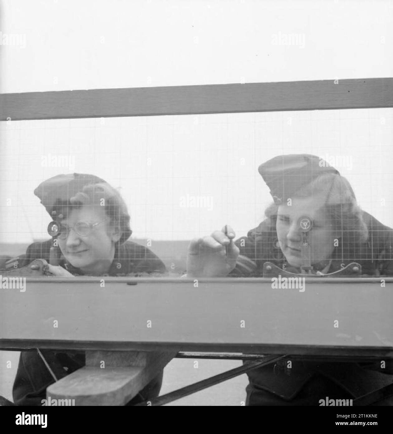 Ragazza Gunners- il lavoro di ausiliari di servizio territoriale in corrispondenza di una stazione sperimentale, Shoeburyness, Essex, Inghilterra, 1943 20 anni privato ATS Eileen Rene e 21 anno vecchio Caporale Susan Bevan al lavoro sulla posizione della finestra Finder presso il Royal Artillery Stazione sperimentale a Shoeburyness. Il vetro della finestra Finder posizione è inciso con una griglia come un foglio di carta millimetrata. Guardando attraverso i telespettatori, le donne mark sulla griglia di partenza la posizione del burst di shell nel cielo, o se la pistola è stato sparato al di sopra del mare, il punto in cui la shell ha colpito l'acqua. La posizione è poi trasferita su carta in Foto Stock