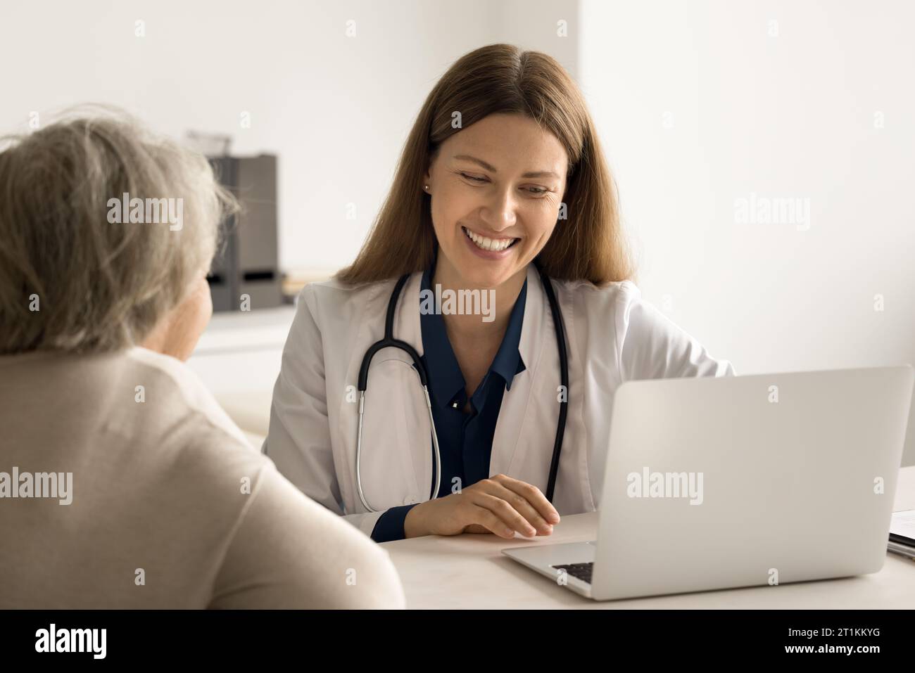 Medico che consulta il notebook di un paziente anziano Foto Stock