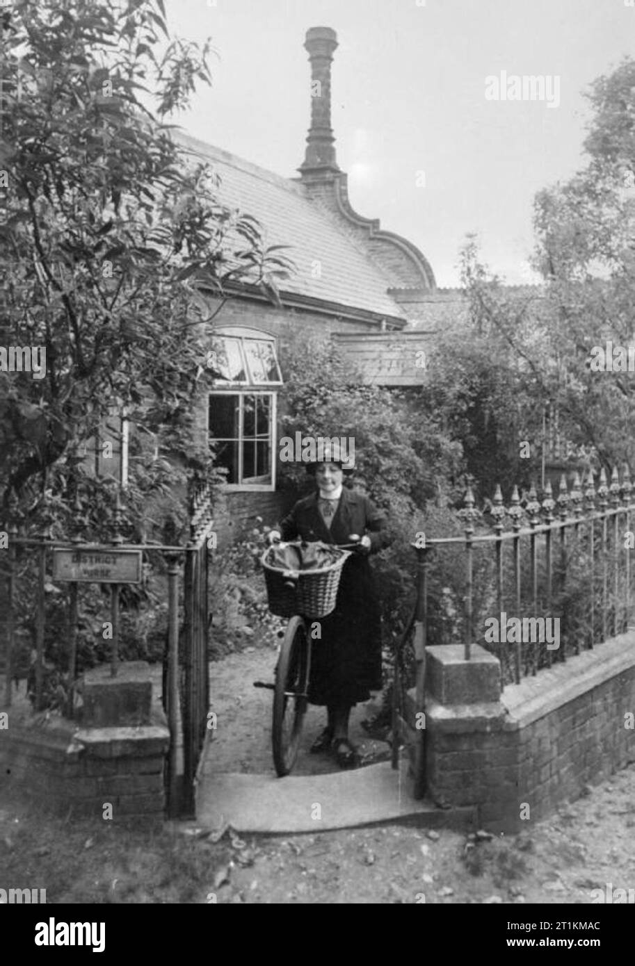 Il villaggio di invasione- La vita quotidiana in Orford, Suffolk, Inghilterra, 1941 District Nurse Baker spinge la sua bicicletta fuori dal suo cancello anteriore come lei lascia la sua casa su una chiamata. L'infermiera Baker è il responsabile della locale Posti di primo soccorso e è anche sul comitato di invasione. Foto Stock