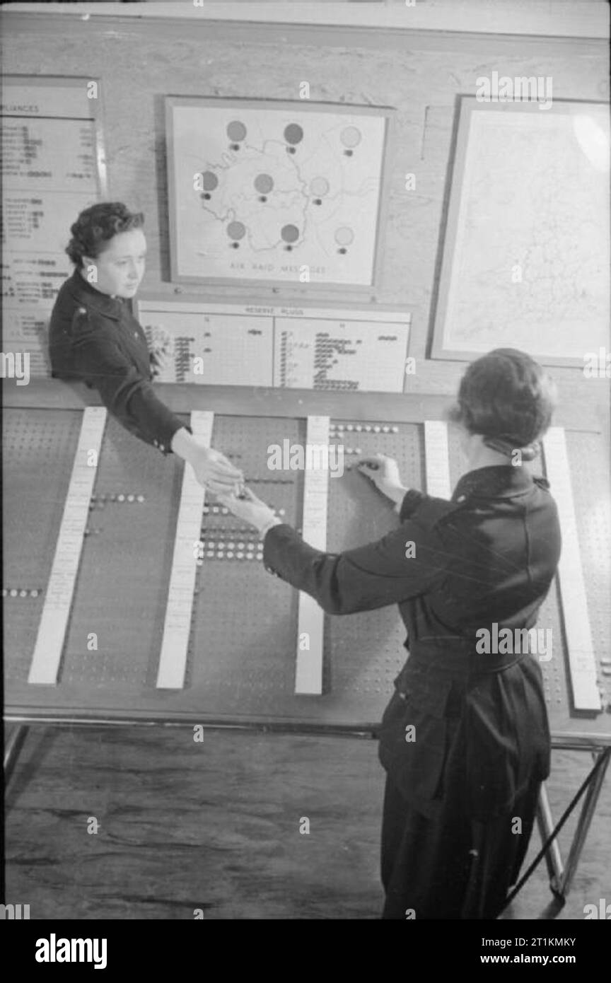 Londra Afs- Uomini di ausiliari di servizio antincendio a Londra, C 1940 Due donne del fuoco ausiliario di servizio al lavoro nella sala di controllo della London Fire Brigade Headquarters. Essi stanno mettendo pioli del marcatore in un consiglio di amministrazione che si riferisce a talune zone di Londra, che sono ciascuna data una lettera dell alfabeto per identificare ciascun gruppo. I pioli che probabilmente rappresentano posizioni di incendi o di pompe in varie parti di Londra. Foto Stock