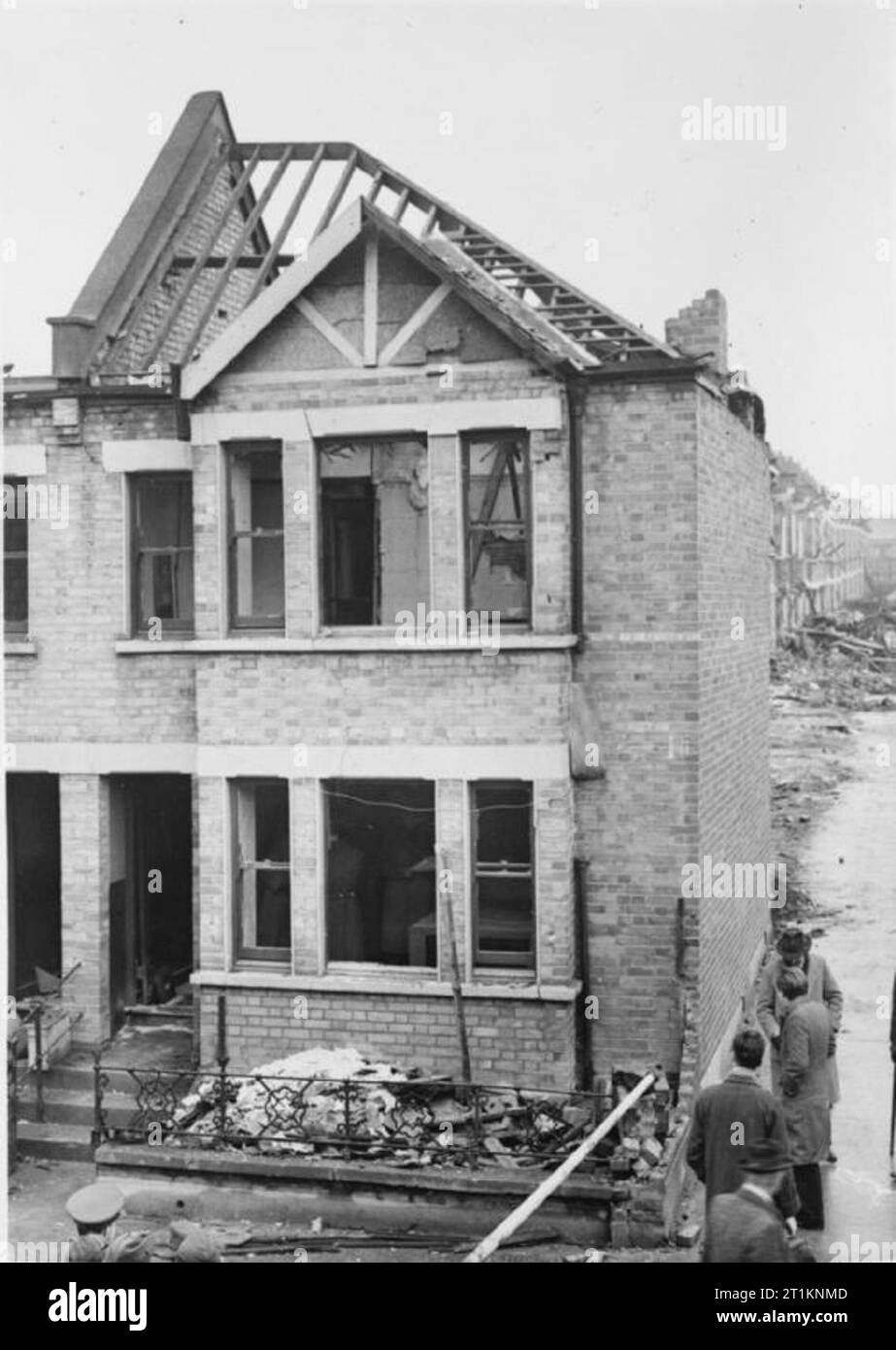 Morrison Shelter in prova- test del nuovo rifugio interno, 1941 uomini, probabilmente dal ministero della Sicurezza domestica, controllare l'interno e al di fuori di casa per essere utilizzata in questa prova di una piscina tabella-tipo air raid shelter, da qualche parte in Gran Bretagna nel 1941. Sembra che questo Parlamento e la zona circostante era già stato gravemente danneggiato in un raid aereo. Foto Stock