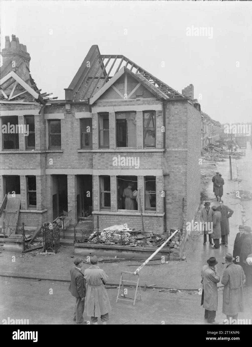 Morrison Shelter in prova- test del nuovo rifugio interno, 1941 uomini, probabilmente dal ministero della Sicurezza domestica, controllare l'interno e al di fuori di casa per essere utilizzata in questa prova di una piscina tabella-tipo air raid shelter, da qualche parte in Gran Bretagna nel 1941. Sembra che questo Parlamento e la zona circostante era già stato gravemente danneggiato in un raid aereo. Foto Stock