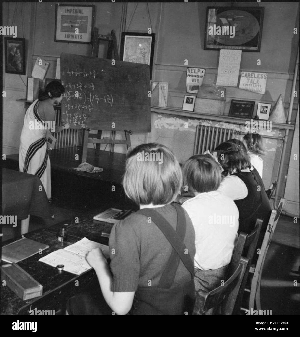 La guerra arriva a scuola- Vita a Peckham Scuola centrale di Londra, Inghilterra, 1943 bambini in forma 1 a Peckham Scuola centrale ascoltare insegnante Miss Sengoupta, dall'India, in quanto essa dà loro una lezione di matematica. Miss Sengoupta ha scritto un numero di somme sulla lavagna. Vari disegnati a mano poster possono essere viste intorno alla camera, tra cui uno che sconsigliano la incurante parlare. Secondo la didascalia originale, Miss Sengoupta ha svolto attività didattica presso la scuola per circa un mese, e oggi la sua sari è rosa. Foto Stock