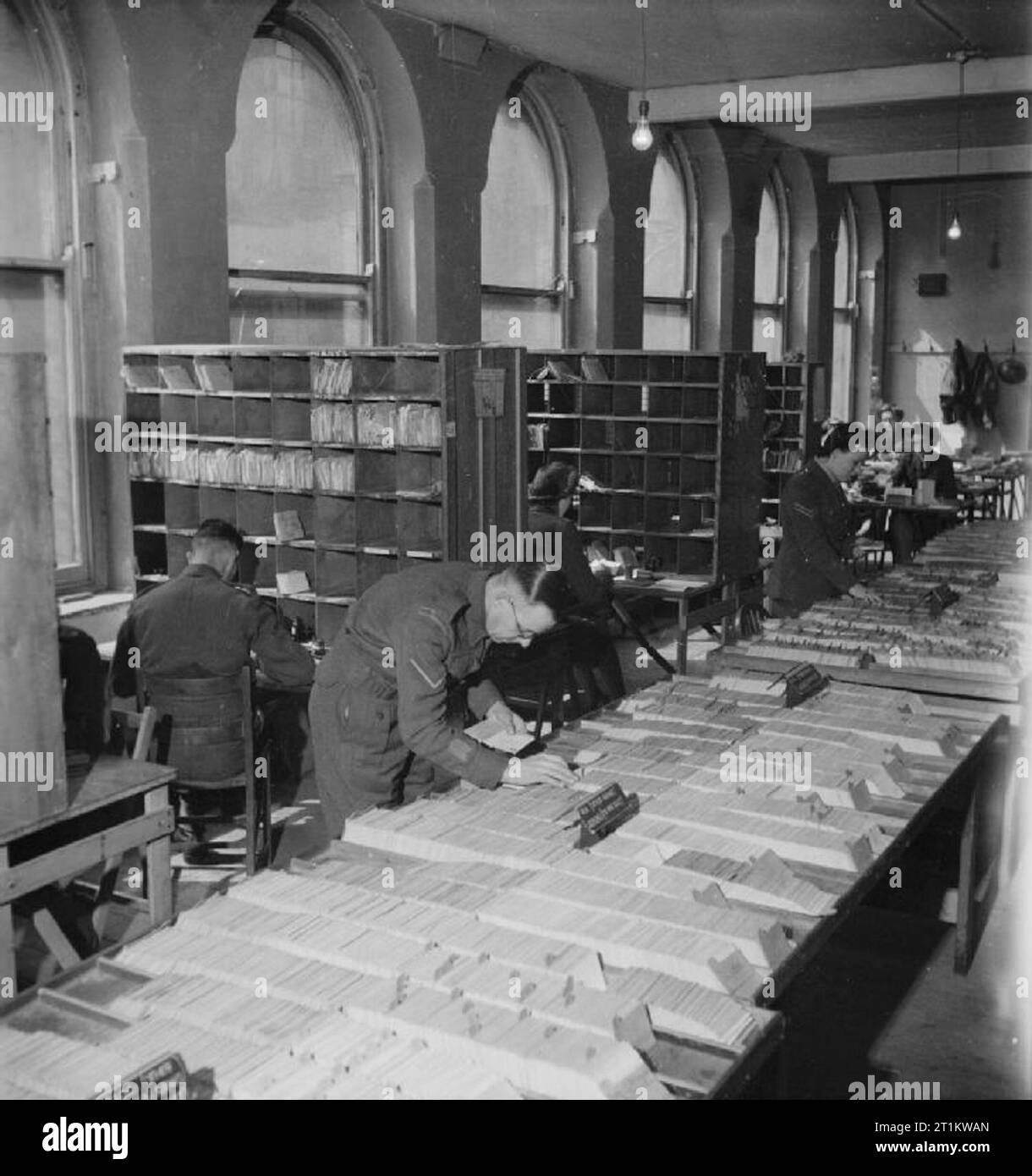 Army Post Office nelle Midlands, Inghilterra, 1944 Personale dell'esercito Post Office 'somewhere nelle Midlands' lavorare sulla scheda Indice di due milioni di morti che è mantenuto. Questo indice abilitato lettere per i prigionieri per essere inviato alla Croce Rossa per la consegna, e abilitato lettere per ferite al personale di assistenza di essere inviati al corretto ospedale. Ciò significava inoltre che i parenti prossimi dei morti potrebbe avere le proprie lettere restituiti dopo che avevano ricevuto la loro guerra ufficiale ufficio notifica. In background, più personale può essere visto lo smistamento della posta. Foto Stock