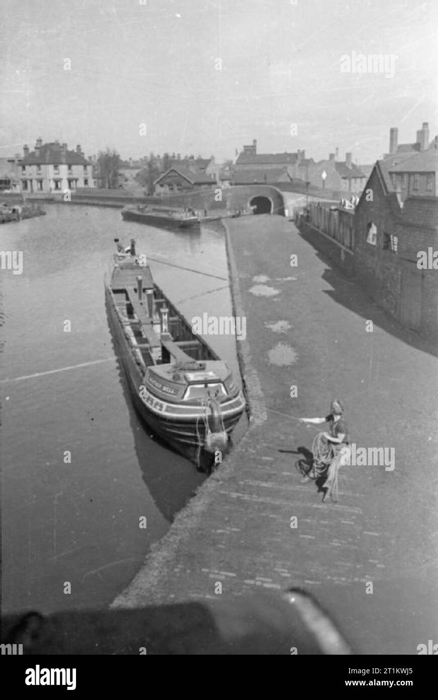 Le donne correre una barca- La vita a bordo della chiatta sul canale "heather Bell', 1942 Dopo lo scarico della motonave Miss marzo altalene "Heather bell' attorno al fine di testa in discesa verso i bacini di raccogliere un carico di lasco. Essi saranno probabilmente viaggiare lontano da Tipton verde sull'Cotterill Colliery ramo del canale di Birmingham. Questa fotografia sembra essere stato preso dal ponte che attraversa il canale. Foto Stock