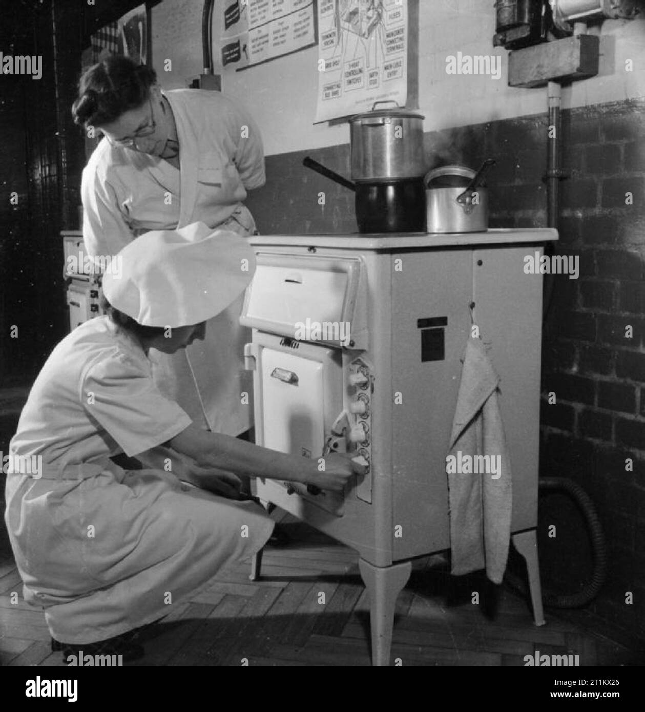 Ats Scienza Nazionale corso- Home Management Training, Notting Hill Gate, London, England, Regno Unito, 1944 Come parte della sua domestica di scienza di formazione presso Avondale Park School in Notting Hill, privato Nora Spink (da Whitby) riceve una lezione nel funzionamento di un fornello elettrico dal Capo istruttore onorevole F M Evans. Pte Spink è un driver in ATS, e spera di poter eseguire la propria piccola azienda dopo la guerra. Foto Stock