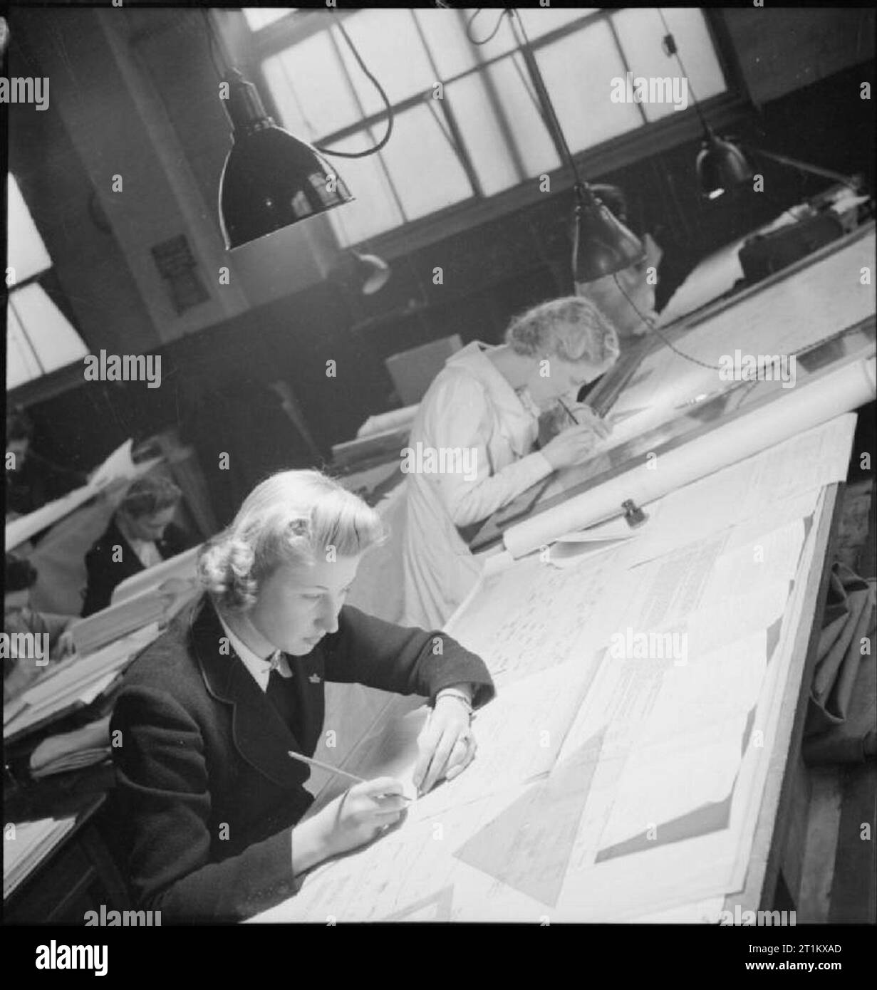Nascita di un bombardiere- produzione di aeromobili in Gran Bretagna, 1942 La signora Peggy Tompkins si siede a un tavolo da disegno e segni sul centro di gravità per le varie parti di aeromobili, all'Handley Page fabbrica a Cricklewood. Molte altre le donne possono anche essere visti al lavoro nel disegno Office. Foto Stock