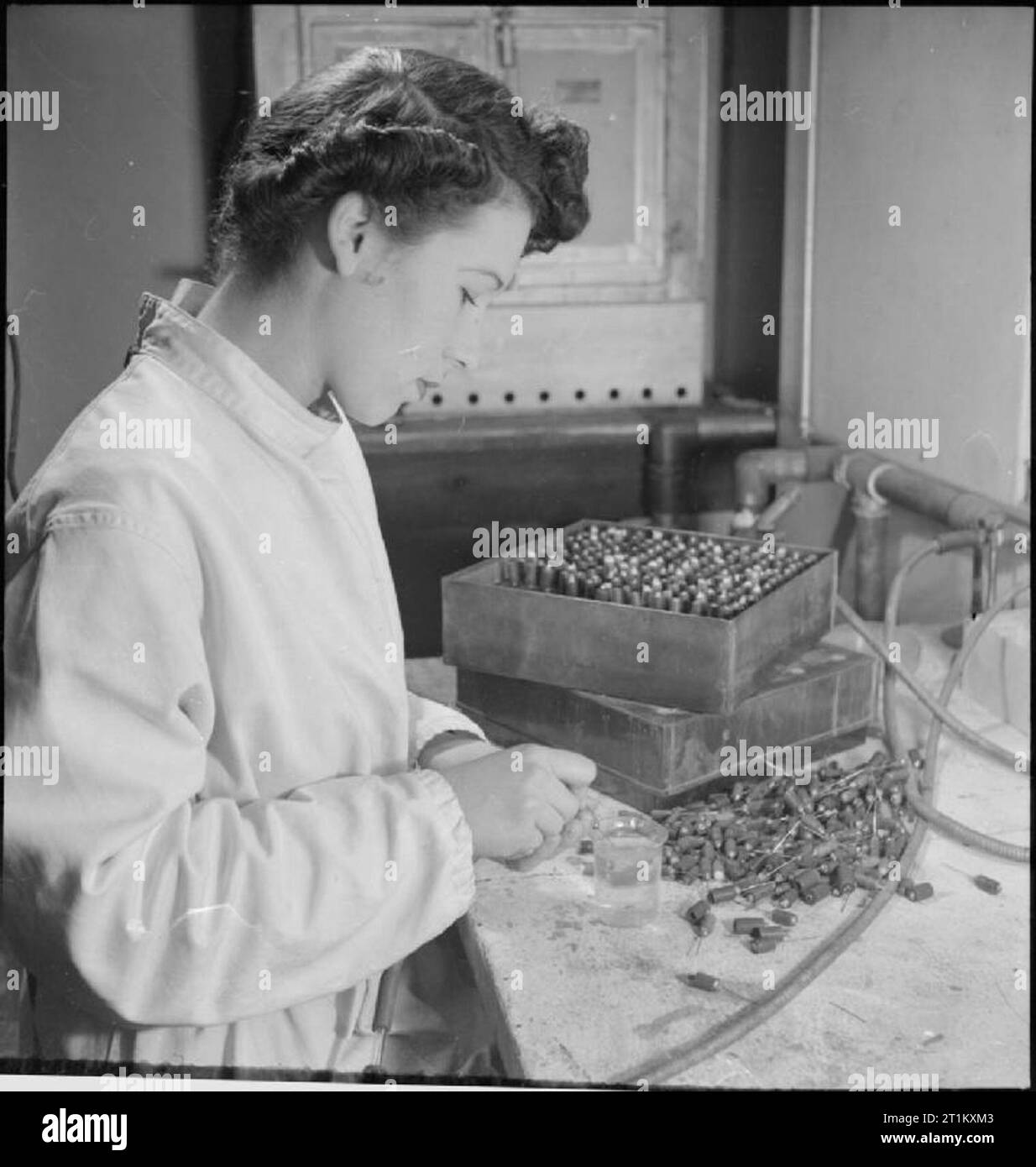 Sangue unità di essiccazione- Il trattamento di sangue in laboratorio, Cambridge, Inghilterra, Regno Unito, 1943 Un lavoratore presso il sangue unità di essiccazione a Cambridge University sterilizza aghi per essere collocati in tappi a vite di bottiglie di plasma. Gli aghi sono equipaggiati con brevi tratti di tubo in gomma contenente lana di cotone per evitare che i germi di entrare le bottiglie. Gli aghi vengono inseriti in una particolare fase del processo di essiccazione. Foto Stock