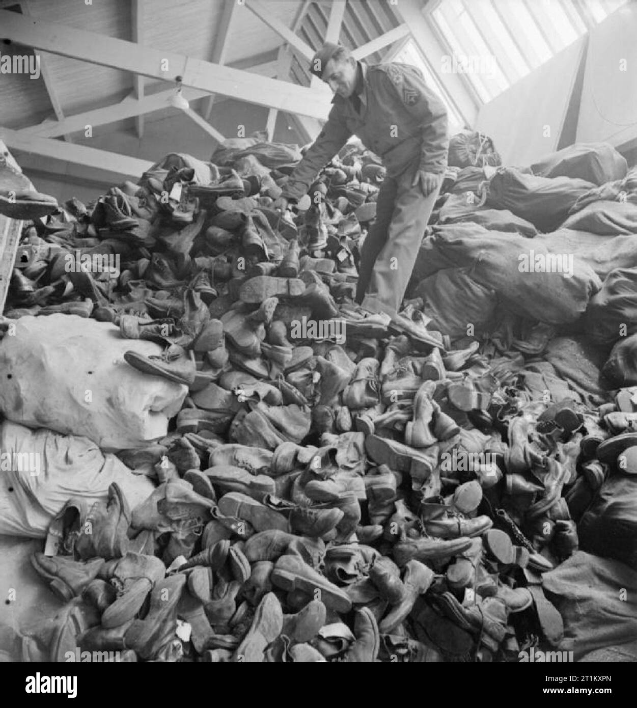 Stivali, stivali, per andare su e giù in Africa- The Salvage and Repair of Army Boots, Somerset, Inghilterra, 1943 Un operaio in questo grande magazzino di una fabbrica di scarpe da qualche parte nel Somerset, si trova su un'enorme pila di stivali militari indossati. Questa montagna di calzature è selezionata e selezionata per la ricostruzione. Circa il 24 per cento non è adatto al riutilizzo dell'esercito e sarà invece riparato e distribuito ai prigionieri di guerra. Foto Stock