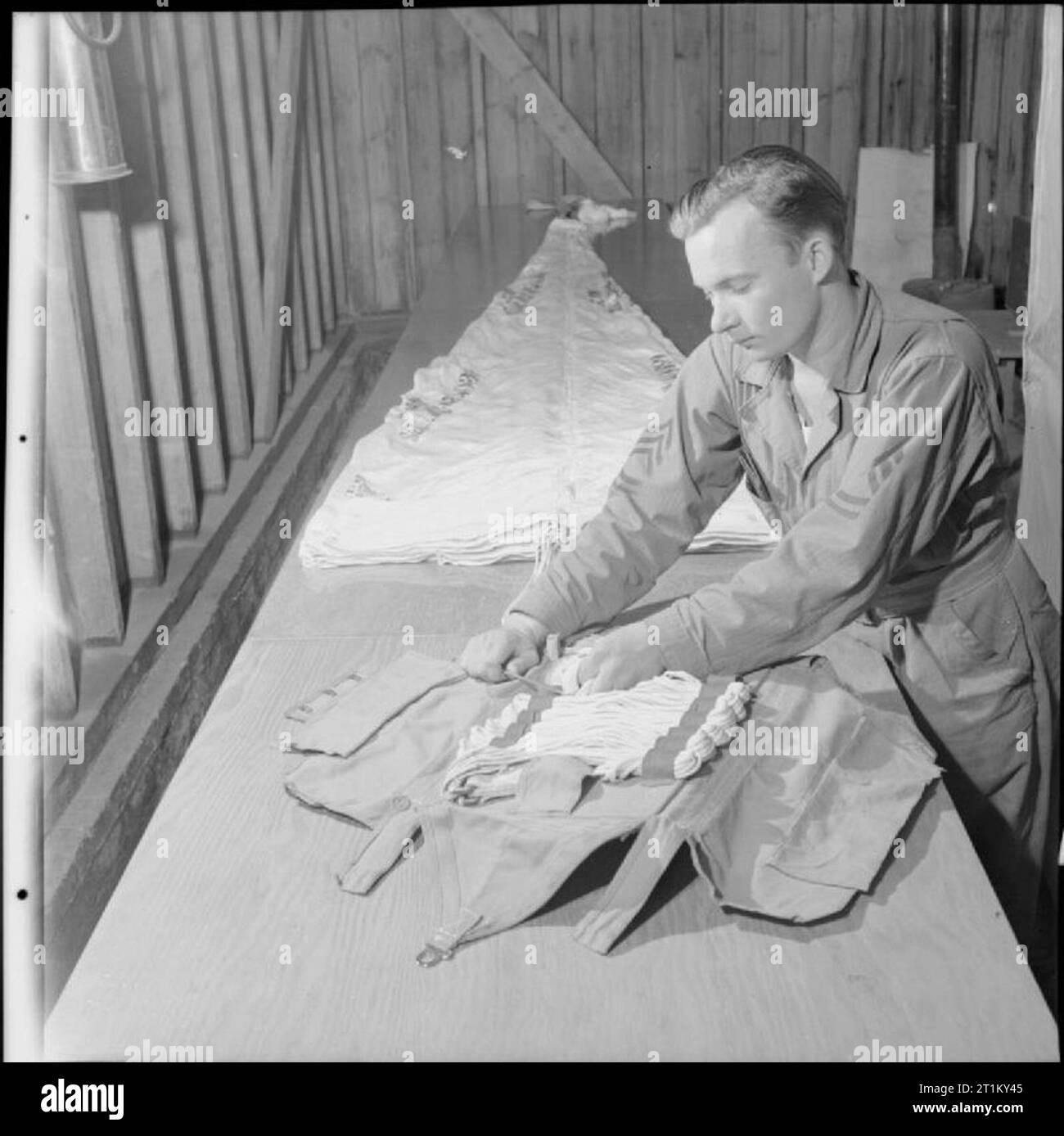 British apparecchiature in un campo di aviazione americana- Anglo-american Co-operazione in tempo di guerra la Gran Bretagna, 1943 Sergente Monette R Foreman da Liberty, Mississippi confezioni un paracadute in un British-fatto paracadute sui cavi in corrispondenza di un campo di aviazione americana, da qualche parte in Gran Bretagna. Foto Stock