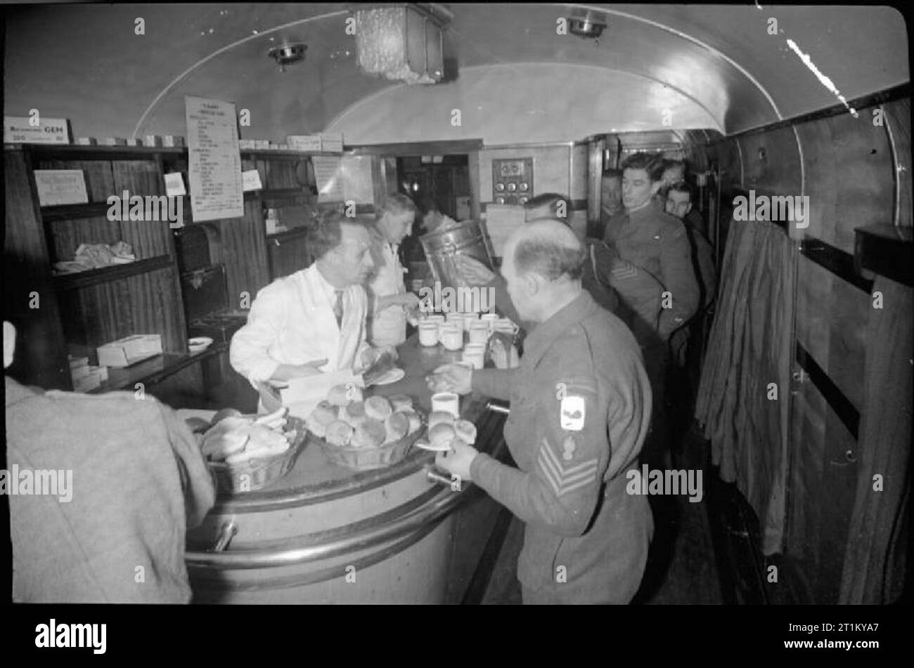 Ferrovie britanniche in tempo di guerra - lasciare il treno- trasporto tra Londra e la Scozia, Regno Unito, 1944 soldati del Royal Engineers in coda fino a acquistare rinfreschi nel buffet auto sul treno di lasciare. Il buffet è gestito dalla NAAFI. Bevande (compresi il tè, caffè, cacao, limonata, osso e Bovril) compreso nel prezzo da 1d a 2d e panini (compresa la lingua, prosciutto, carne di maiale salmistrata, rotolo di carne, formaggio e pasta) compreso nel prezzo da 2d a 6d. L'originale didascalie afferma che in questo buffet i soldati si possono acquistare sigarette 'a 1/6d per 20, il cioccolato senza punti!). Altri spuntini disponibili qui sono dolci e torte Foto Stock