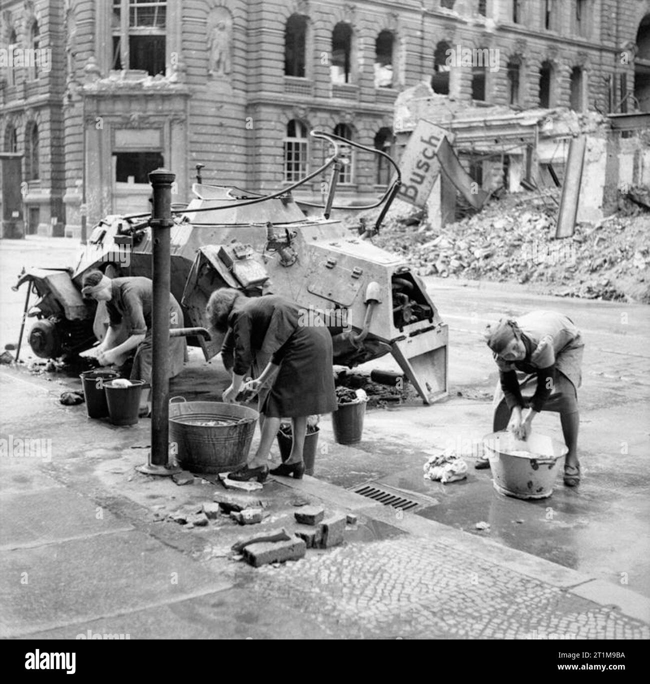 Tedesco donne facendo loro il lavaggio ad un idrante di acqua in una strada di Berlino, vicino al relitto di una luce tedesco autoblindo, 3 luglio 1945. Tedesco donne facendo loro il lavaggio ad un acqua fredda idrante in via Berlino un messo k.o. tedesco auto scout è accanto a loro. Foto Stock